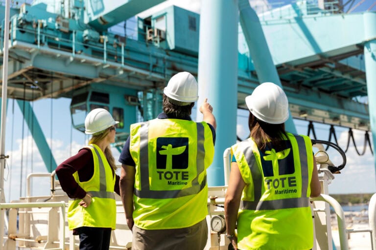 Workers in safety vests and helmets inspecting an offshore platform.