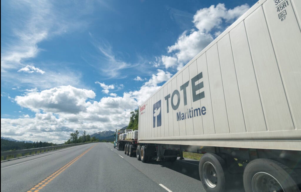 TOTE Maritime truck on the highway under a partly cloudy sky.