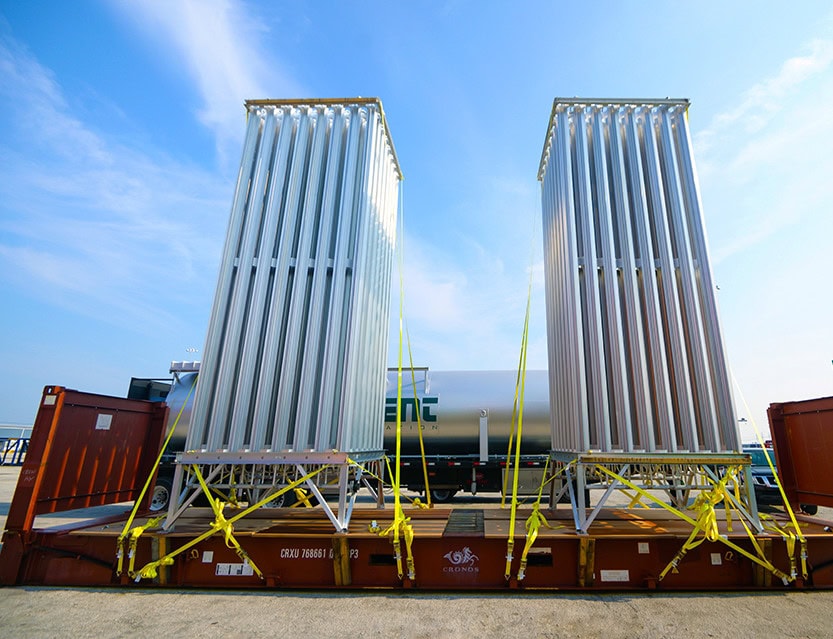 Two large industrial cooling units on a flatbed train car under a blue sky.