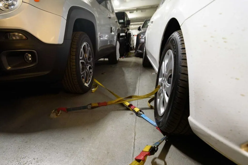 Car wheel secured with towing straps in an indoor parking garage.