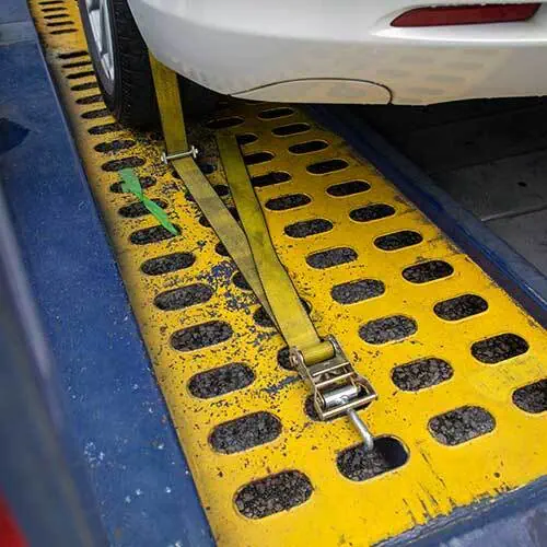 Car wheel secured with a yellow strap on a yellow safety platform.