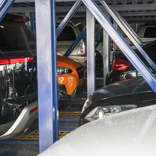 Car parking garage with multiple vehicles parked between blue metal beams.