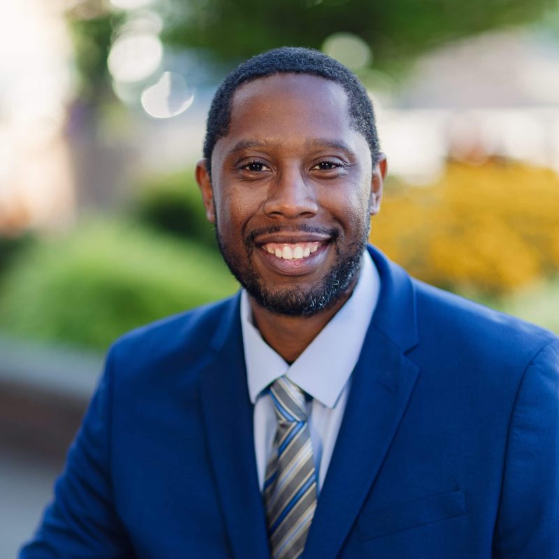 Portrait of a smiling man in a blue suit outdoors.