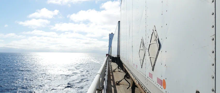 View of the ocean from a ship's deck with a white container on the right side.